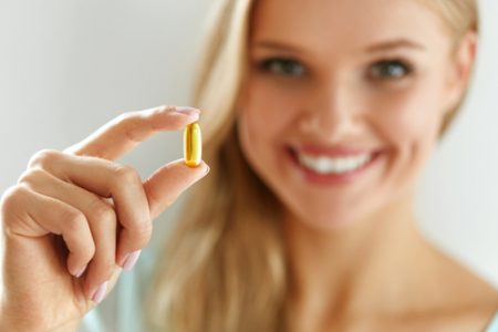 Vitamin,And,Supplement.,Beautiful,Smiling,Woman,Holding,Fish,Oil,Capsule